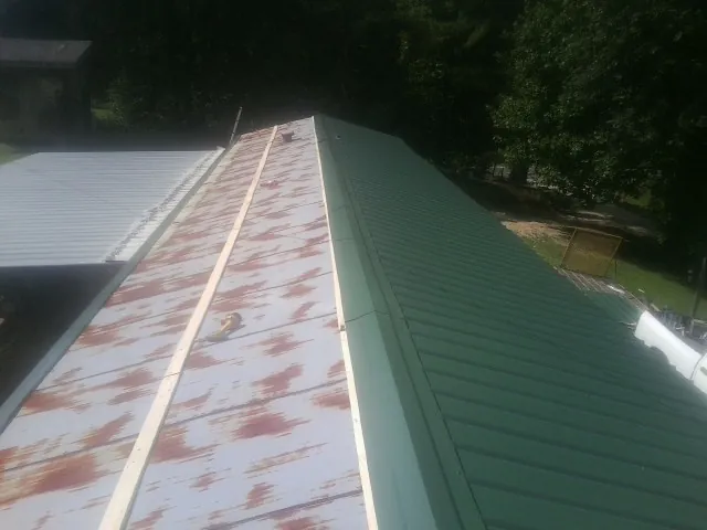 Old rusted panels beside newly installed green metal roofing — Wind Damage Roof Repair by Roofing Brothers in Barkhamsted