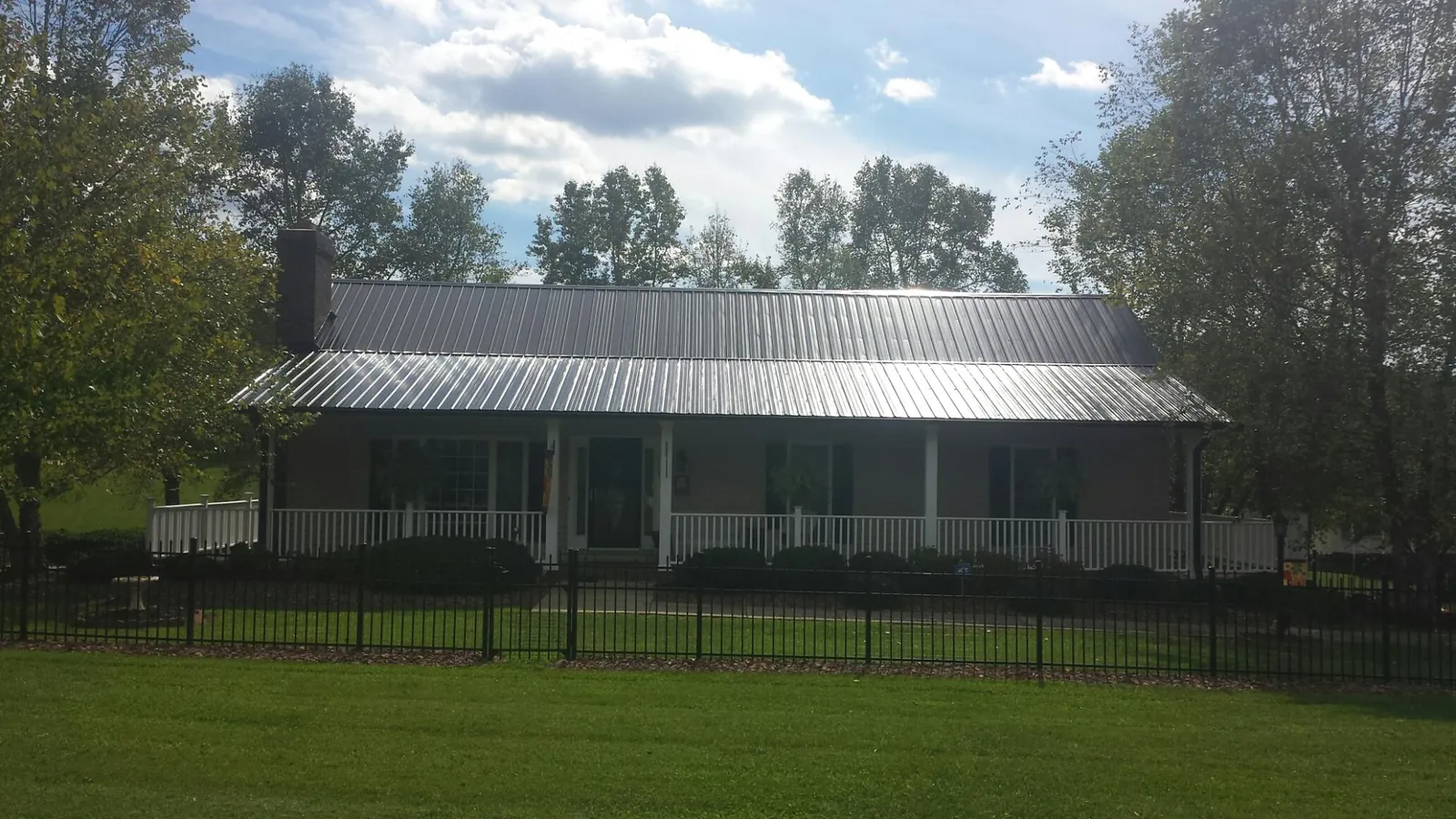 Gray metal roof on a brick ranch with a full width front porch — Gutter Guard Installation work by our crew in Barkhamsted