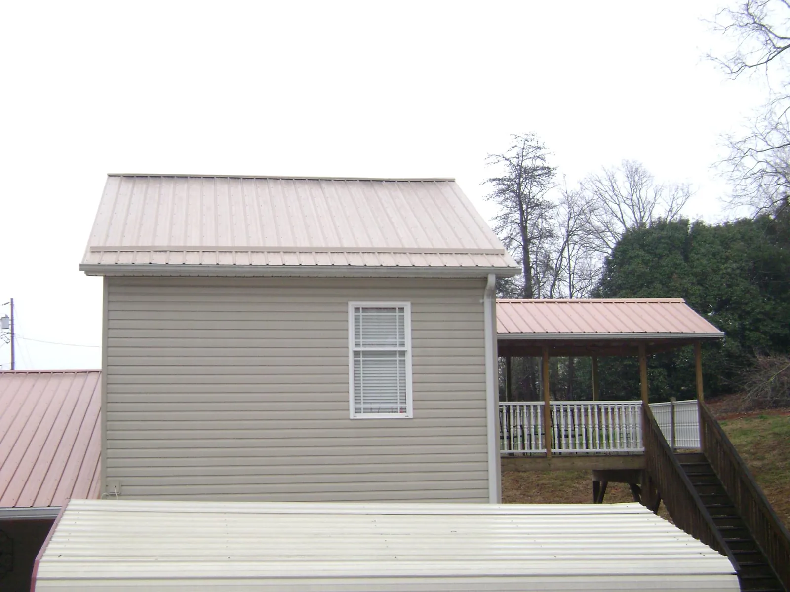 Tan metal roofs on a two story addition and attached porch, from a Roof Replacement job in Barkhamsted