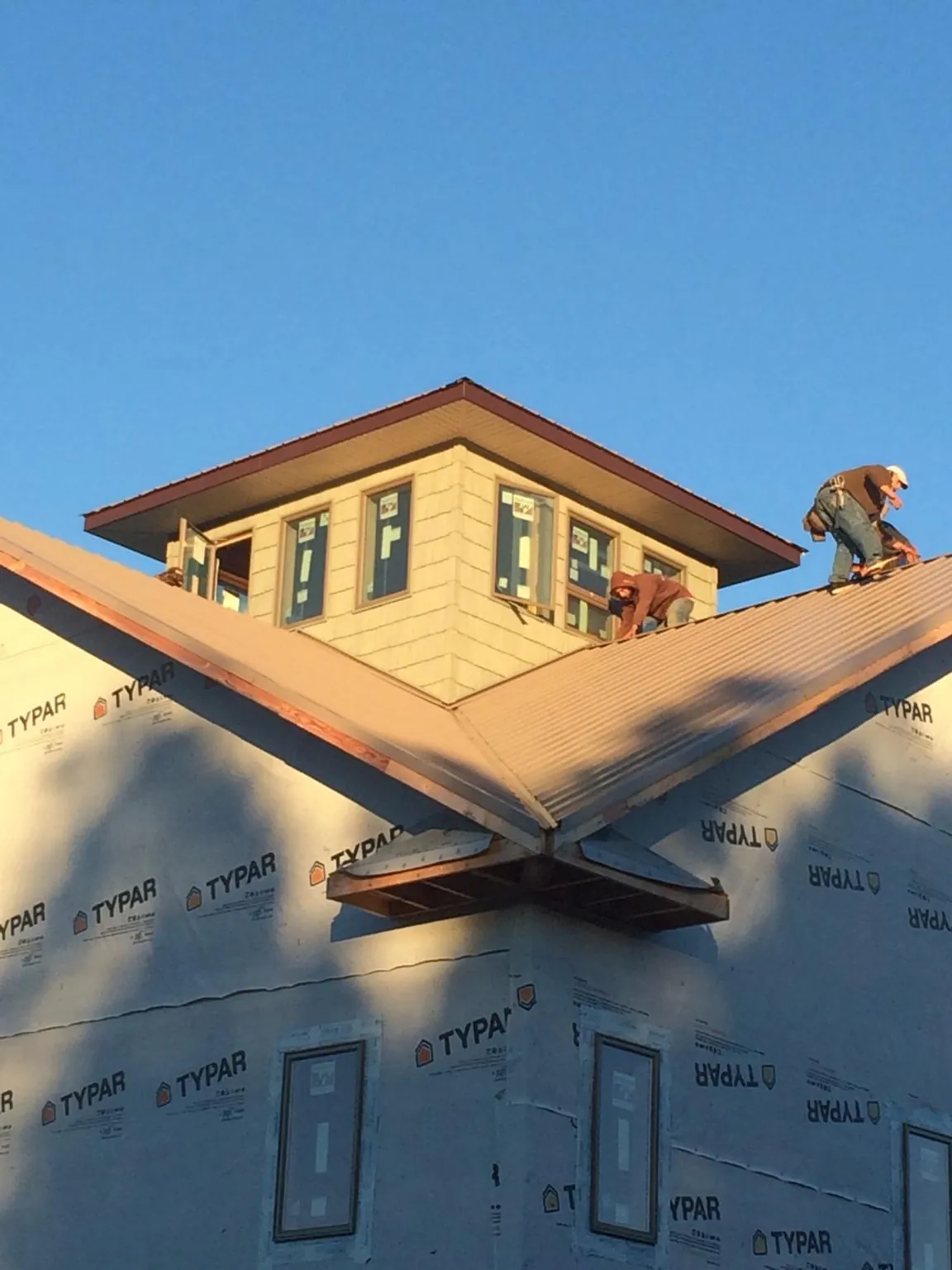 Roofers working around a rooftop cupola on a new metal roof at sunset — Roof Waterproofing in Barkhamsted by Roofing Brothers